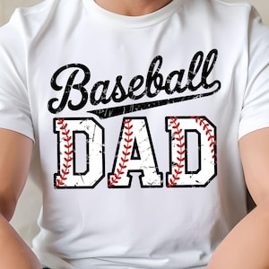 Puede incluir: Camiseta blanca con las palabras "Baseball DAD" en un diseño negro y rojo desgastado. La palabra "Baseball" está en una fuente cursiva, y "DAD" está en negrita, con un tema de béisbol y costuras rojas.