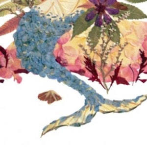 K&ouml;nnte beinhalten: Eine blaue und wei&szlig;e gepresste Blumenarrangements in Form einer Meerjungfrau. Der Schwanz der Meerjungfrau ist eingerollt und der obere Teil der Meerjungfrau besteht aus Blumen.