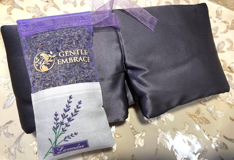 May include: A dark blue eye mask and a small sachet of lavender. The sachet is purple mesh filled with dried lavender buds and has the words "GENTLE EMBRACE" printed on it. A lavender sprig is embroidered on the white bottom of the sachet.