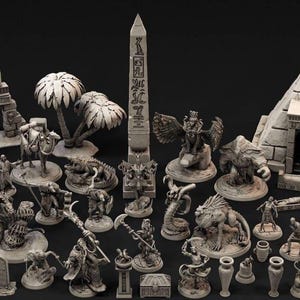 Op de afbeelding: Een verzameling miniatuurfiguren en structuren met een oud-Egyptisch thema. Inclusief een piramide, obelisk, beelden, palmbomen en diverse mythische wezens. De stukken zijn allemaal in een neutrale, steenachtige kleur.