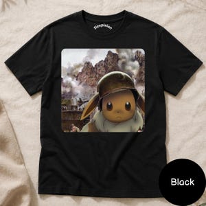 May include: A black short-sleeve t-shirt featuring a graphic print of a brown Eevee character wearing a military helmet. The background of the print shows a smoky, mountainous battlefield scene. The inner neck label displays the text Sleeplalan.