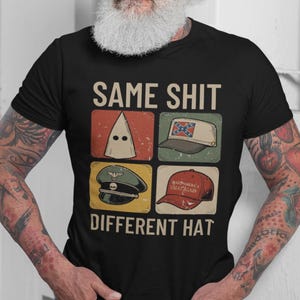 May include: Black t-shirt featuring the text "SAME SHIT DIFFERENT HAT" above a graphic of four different hats. The hats include a white hood, a baseball cap with a Confederate flag, a military hat, and a red "Make America Great Again" hat.