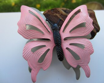 May include: A pink metal butterfly with black accents. The butterfly has a cut-out design and a textured surface.