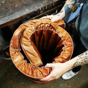 Handmade buffalo leather gym mat being rolled up by hand, illustrating its flexibility and practicality. The piece can easily be stored or moved, making it perfect for dynamic interiors or home gym spaces that value both beauty and function.