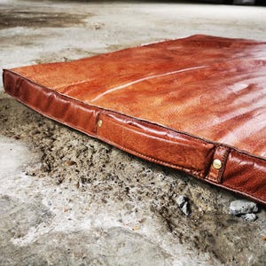 Perspective view of the large buffalo leather tatami placed on a concrete industrial floor. The smooth patina and natural variations of the leather make it a perfect decorative rug for home gyms, studios, or loft-style interiors seeking authentic handmade pieces.