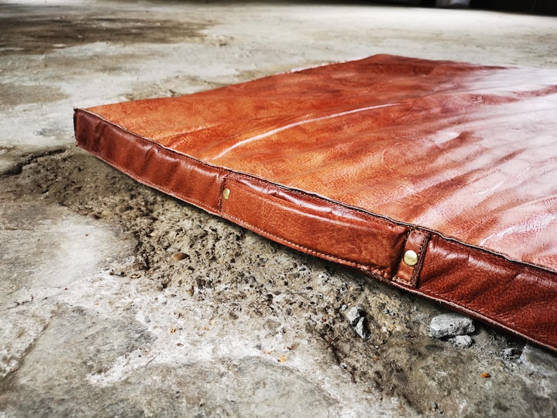 Perspective view of the large buffalo leather tatami placed on a concrete industrial floor. The smooth patina and natural variations of the leather make it a perfect decorative rug for home gyms, studios, or loft-style interiors seeking authentic handmade pieces.