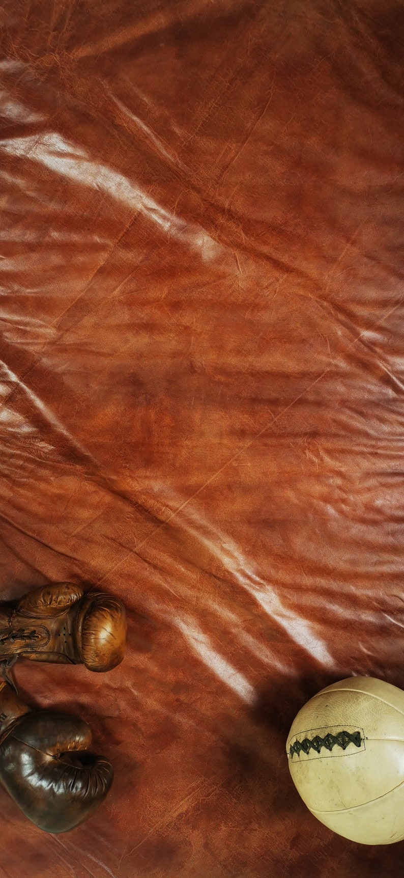 Detail shot of the buffalo leather patina with visible engraving mark and fine stitches. The soft mineral-tanned surface reflects warm brown and caramel tones, showcasing authentic handmade quality and premium craftsmanship for collectors and interior designers.
