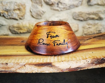May include: A wooden bowl with a natural wood finish. The bowl is engraved with the text "From Roux Family".