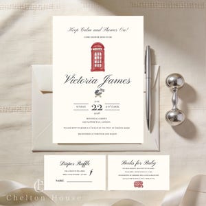 May include: Cream-colored baby shower invitation with a red telephone booth illustration. The invitation includes the text "Keep Calm and Shower On!" and "Victoria James". A silver pen and rattle are also present.