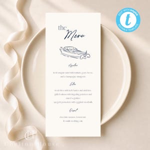 Peut inclure: Une carte de menu crème avec les mots "the Menu" en écriture élégante, avec une illustration de bateau. Le menu répertorie les entrées, les plats et les desserts. La carte est sur une assiette blanche avec un ruban crème.