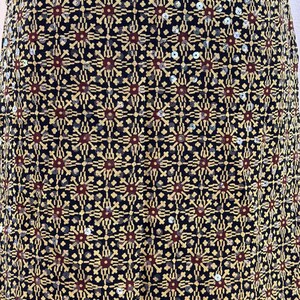 May include: A black fabric skirt featuring a repeating geometric pattern in gold and dark red. The design consists of star-like motifs arranged in a grid, accented with small, reflective silver sequins scattered throughout the entire surface.