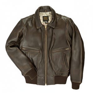 May include: A brown leather bomber jacket with a zip-up front, two front pockets, and a ribbed collar and cuffs. The jacket has a map-like pattern on the inside lining. The jacket is a classic style.