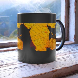 Puede incluir: Taza de cerámica negra con diseño de Halloween. El diseño incluye siluetas negras de murciélagos y una telaraña sobre un fondo amarillo. La taza está sobre un alféizar de madera blanco.