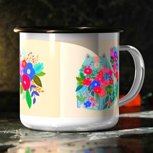 K&ouml;nnte beinhalten: Ein wei&szlig;er Emaillebecher mit schwarzem Rand und silbernem Henkel. Der Becher zeigt eine bunte Grafik einer hellblauen Katze, die mit leuchtend roten, rosa und blauen Blumen bedeckt ist, sowie ein separates Blumenstrau&szlig;-Design auf cremefarbenem Grund.