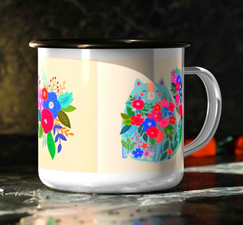 K&ouml;nnte beinhalten: Ein wei&szlig;er Emaillebecher mit schwarzem Rand und silbernem Henkel. Der Becher zeigt eine bunte Grafik einer hellblauen Katze, die mit leuchtend roten, rosa und blauen Blumen bedeckt ist, sowie ein separates Blumenstrau&szlig;-Design auf cremefarbenem Grund.