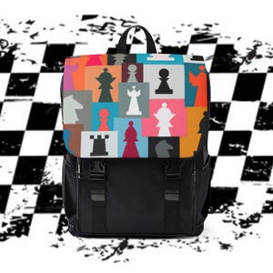 May include: A black backpack featuring a top flap with a multi-colored geometric pattern of various chess piece silhouettes in shades of orange, blue, pink, gray, and white. The bag includes two black vertical straps with plastic buckle closures.