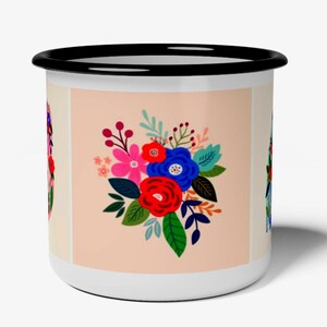 K&ouml;nnte beinhalten: Ein wei&szlig;er Emaillebecher mit schwarzem Rand und einem zentralen quadratischen Feld auf hellpfirsichfarbenem Hintergrund. Das Feld zeigt einen lebendigen Blumenstrau&szlig; mit roten, blauen und rosa Bl&uuml;ten, gr&uuml;nen Bl&auml;ttern und Beeren, wobei an den Seiten weitere florale Motive teilweise sichtbar sind.