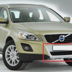 Może przedstawiać: Jasnozielony SUV Volvo XC60. Widoczny jest przód pojazdu, prezentujący kratkę z emblematem Volvo, reflektory i srebrny zderzak. Opony są czarne, a felgi srebrne.