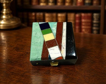 May include: A square box featuring a geometric inlay pattern of polished stone segments in shades of mint green, dark blue, forest green, cream, reddish-brown, white marble, and solid black, with a metallic latch on the front edge.