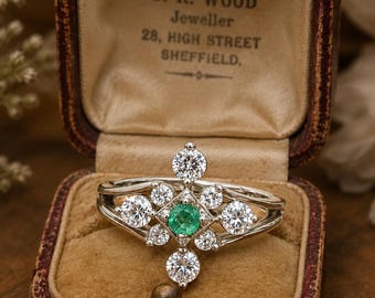 May include: A silver ring featuring a central round green gemstone surrounded by eight clear round stones in a starburst arrangement. The ring is displayed in a vintage brown velvet-lined box with the text J. R. WOOD Jeweller 28, HIGH STREET SHEFFIELD.