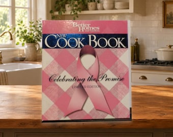 May include: A Better Homes and Gardens New Cook Book with a pink and white checkered cover featuring a large pink ribbon in the center. The text reads New Cook Book, Celebrating the Promise, and Limited Edition in black and white lettering.