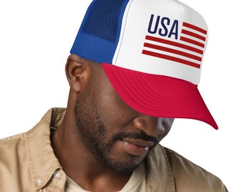 May include: A red, white, and blue trucker hat with the word "USA" and a flag design on the front. The hat has a red brim, a white front panel, and a blue mesh back. The hat is worn by a person.