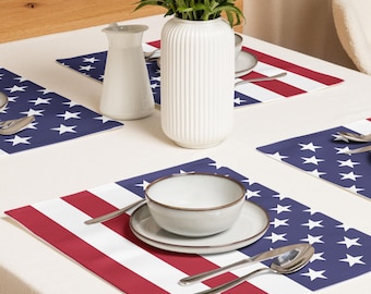Peut inclure: Mise en place avec des sets de table aux couleurs du drapeau américain. Les sets de table présentent des rayures rouges et blanches et un champ bleu avec des étoiles blanches. Un vase et un pichet blancs sont sur la table, avec un bol, une assiette et des couverts.