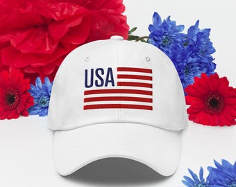 May include: A white baseball cap with the word "USA" in navy blue and a red and white flag design. The cap is surrounded by red and blue flowers, creating a patriotic theme.