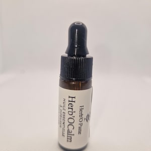 Peut inclure: Une petite bouteille en verre brun avec un bouchon compte-gouttes noir. L'étiquette indique "Herb'O Calm" et "Huile Essentielle à Diffuser". La bouteille contient un liquide, probablement une huile essentielle, et est conçue pour un diffuseur.