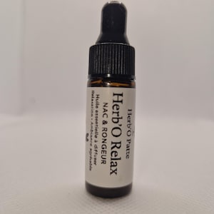 Peut inclure: Petite bouteille en verre brun avec un bouchon compte-gouttes noir. L'étiquette indique "Herb'O Relax" et "NAC & RONGEUR". Contient une huile essentielle pour la relaxation et une ambiance agréable.