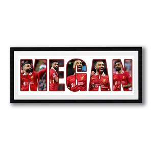 May include: A framed print featuring the name "MEGAN" with each letter filled with images of a soccer player in a red jersey. The frame is black, and the background is white.