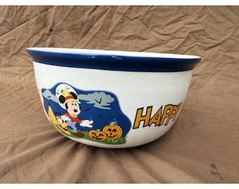 May include: White ceramic bowl with a blue rim and a Halloween-themed Mickey Mouse graphic. The bowl features Mickey in a costume, pumpkins, and the word "HAPPY" in orange letters. A festive piece for serving.