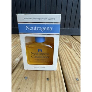 Op de afbeelding: Een witte doos met blauwe accenten bevat een fles Neutrogena Conditioner. De fles is gevuld met een gouden vloeistof en heeft een blauwe dop. Op de doos staat "clean conditioning without coating."