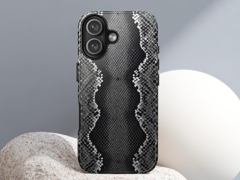 May include: A black and white snakeskin-patterned phone case. The case has a textured appearance and features a dual-lens camera cutout. The design incorporates a central vertical pattern with a wavy edge, creating a striking visual contrast.