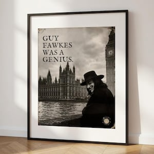 Op de afbeelding: Zwart-wit ingelijste print met een persoon met een hoed en de Houses of Parliament en Big Ben op de achtergrond. De tekst "GUY FAWKES WAS A GENIUS" is weergegeven. De print zit in een zwarte lijst en staat tegen een witte muur.
