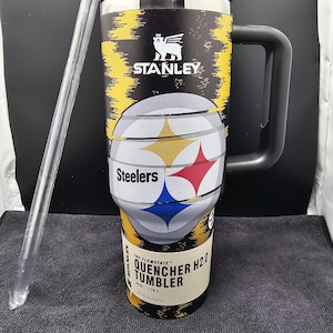 May include: Black and yellow Stanley Quencher H2.0 tumbler with a black handle and lid. The tumbler features the Pittsburgh Steelers logo and team colors. Includes a clear straw. The tumbler is designed for all-day hydration.