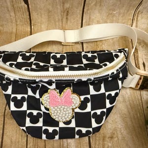 Small crossbody theme park belt bag. Black, white with Mickey head checkered print. Disney Minnie Mouse head patch with pearls and bow pink.