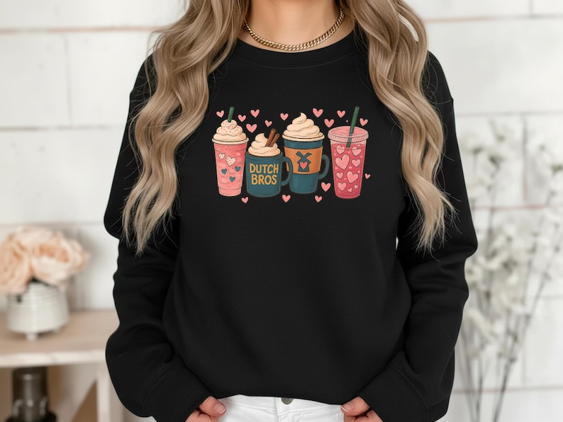 Puede incluir: Sudadera negra con un dise&ntilde;o de cuatro bebidas ilustradas con crema batida, corazones y pajitas. Una taza tiene el texto "DUTCH BROS". El dise&ntilde;o es en rosa, turquesa y marr&oacute;n. Peque&ntilde;os corazones rosas est&aacute;n dispersos.