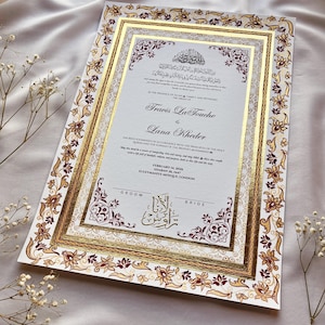 Może przedstawiać: Formalne zaproszenie ślubne ze złotą i bordową kwiatową obw&oacute;dką. Zaproszenie zawiera nazwiska "Travis La Touche" i "Lana Kheder" w eleganckiej czcionce. Tekst zawiera datę 14 lutego 2020 r. i lokalizację Suleymaniye Mosque, Londyn.