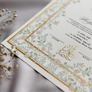 May include: Elegant wedding invitation with floral border in pastel colors. The invitation features gold foil accents and text, including the date April 15, 2025, and the city of Chicago, Illinois, USA. The words "Groom" and "Bride" are also visible.