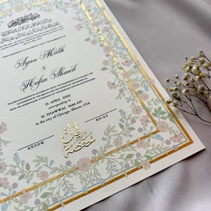 May include: A wedding certificate with floral border in pastel colors and gold accents. The names Ayan Malik and Hafsa Ahmed are featured, along with the date April 15, 2025. The certificate includes Arabic script and is for a wedding in Chicago, Illinois.