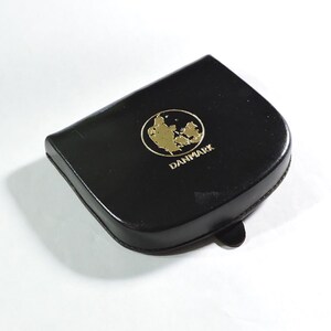 May include: A black leather coin purse with a gold embossed map of Denmark and the word "DANMARK" underneath.