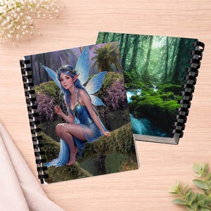 Puede incluir: Dos cuadernos de espiral con ilustraciones vibrantes. Una portada muestra a un hada de pelo azul con alas translúcidas en un bosque, mientras que la otra muestra un bosque verde con un arroyo y rocas cubiertas de musgo.