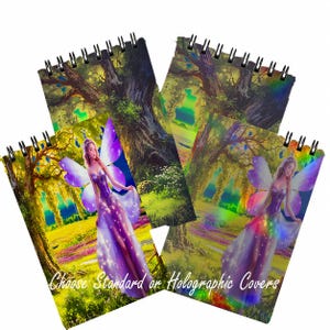 May include: Two spiral-bound notebooks featuring a fantasy illustration of a winged figure in a purple dress standing in a forest landscape. The text "Choose Standard or Holographic Covers" is printed in white script across the bottom of the notebooks.