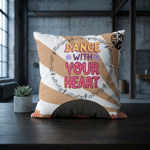 May include: Square decorative pillow with a retro design. The pillow features a tan and white striped background with the words "DANCE WITH YOUR HEART" in colorful text. A disco ball and musical notes complete the design.