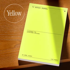 Op de afbeelding: Een felgeel notitieboek met de tekst "TV SERIES JOURNAL" en "A NOTEBOOK FOR INTENTIONAL WATCHING." Het notitieboek is van K&uuml;&ntilde;el Studio en heeft 120 pagina's. Het notitieboek ligt op een houten oppervlak.
