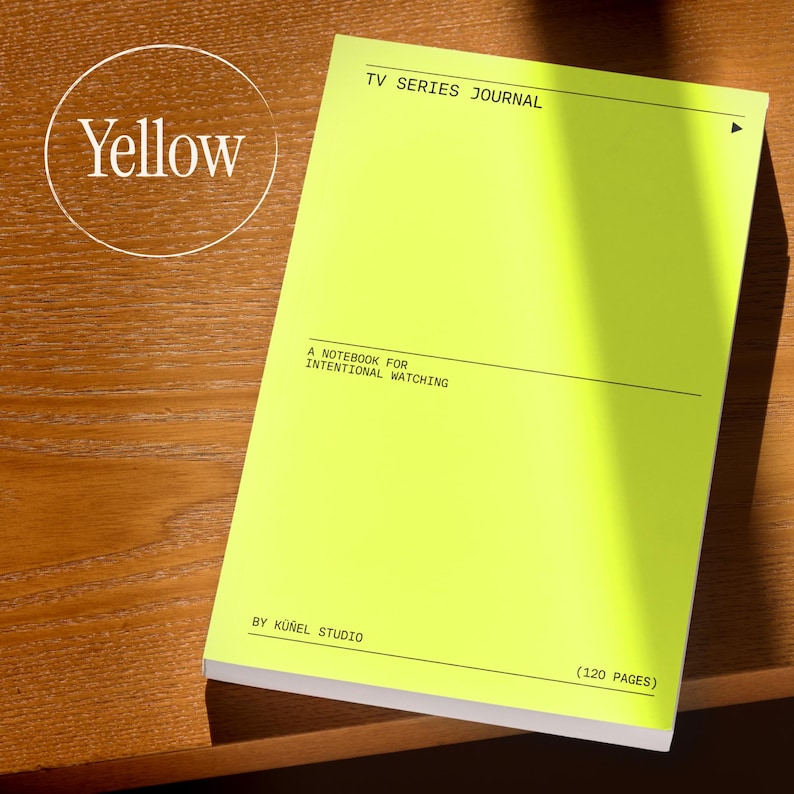 Op de afbeelding: Een felgeel notitieboek met de tekst "TV SERIES JOURNAL" en "A NOTEBOOK FOR INTENTIONAL WATCHING." Het notitieboek is van K&uuml;&ntilde;el Studio en heeft 120 pagina's. Het notitieboek ligt op een houten oppervlak.