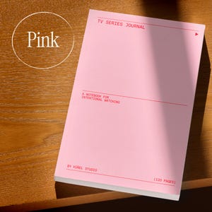 Op de afbeelding: Een roze notitieboek met de tekst "TV SERIES JOURNAL" en "A NOTEBOOK FOR INTENTIONAL WATCHING" in het rood gedrukt. Het notitieboek heeft 120 pagina's en is van K&uuml;nel Studio. Het woord "Pink" staat in een cirkel linksboven.