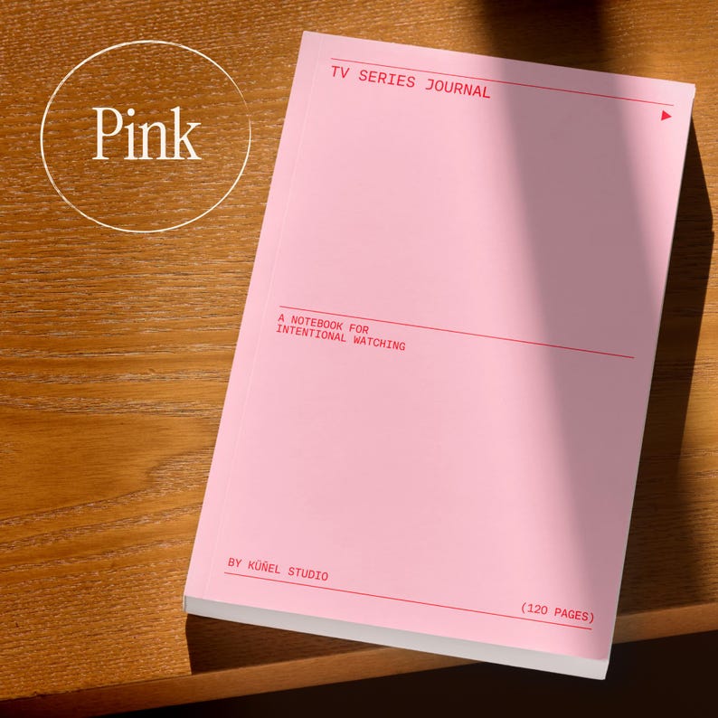 Op de afbeelding: Een roze notitieboek met de tekst "TV SERIES JOURNAL" en "A NOTEBOOK FOR INTENTIONAL WATCHING" in het rood gedrukt. Het notitieboek heeft 120 pagina's en is van K&uuml;nel Studio. Het woord "Pink" staat in een cirkel linksboven.
