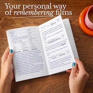 Op de afbeelding: Een open notitieboek met filmrecensies, met de tekst "Your personal way of remembering films". De linkerpagina bevat een recensie van "Euphoria" met handgeschreven notities. De rechterpagina bevat meer recensies. Een kopje koffie staat op de achtergrond.